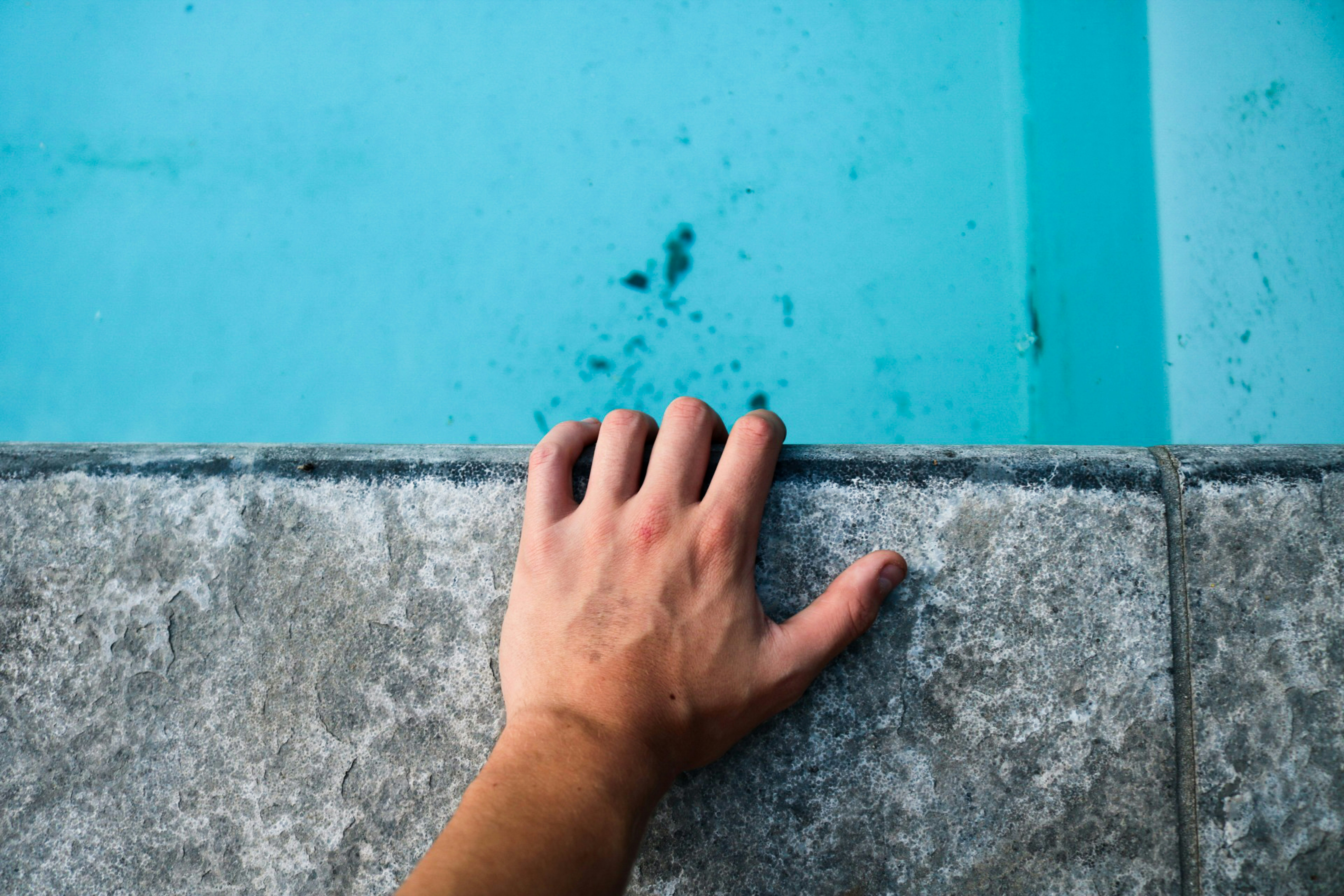 person's left hand holding gray concrete surface